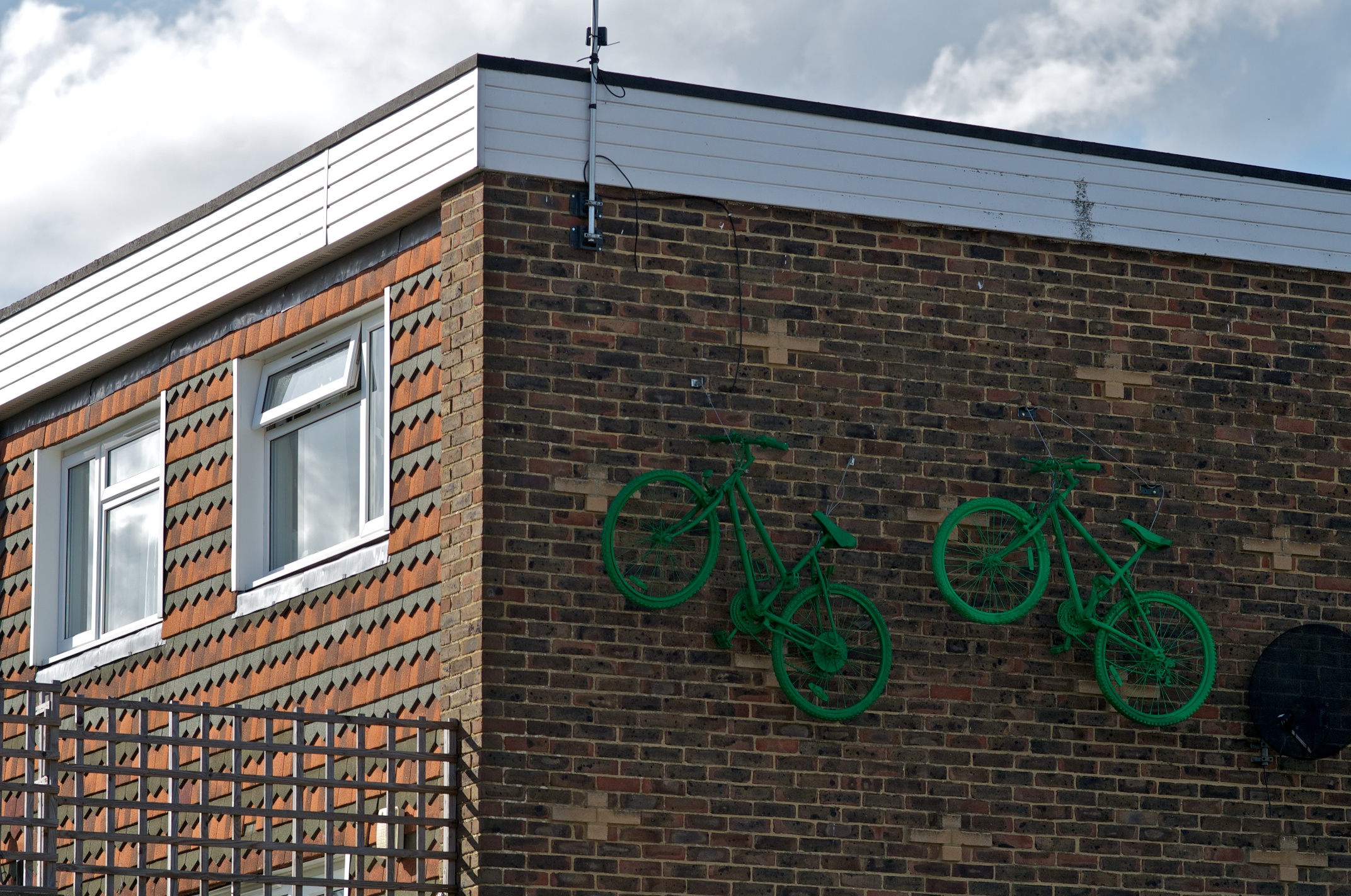 Two green bikes 'sit' at the top of a brick wall